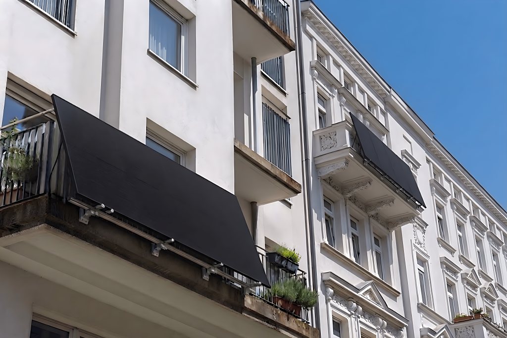 Zwei Balkonkraftwerke mit Solarmodulen an den Balkonbrüstungen eines Altbaus vor blauem Himmel